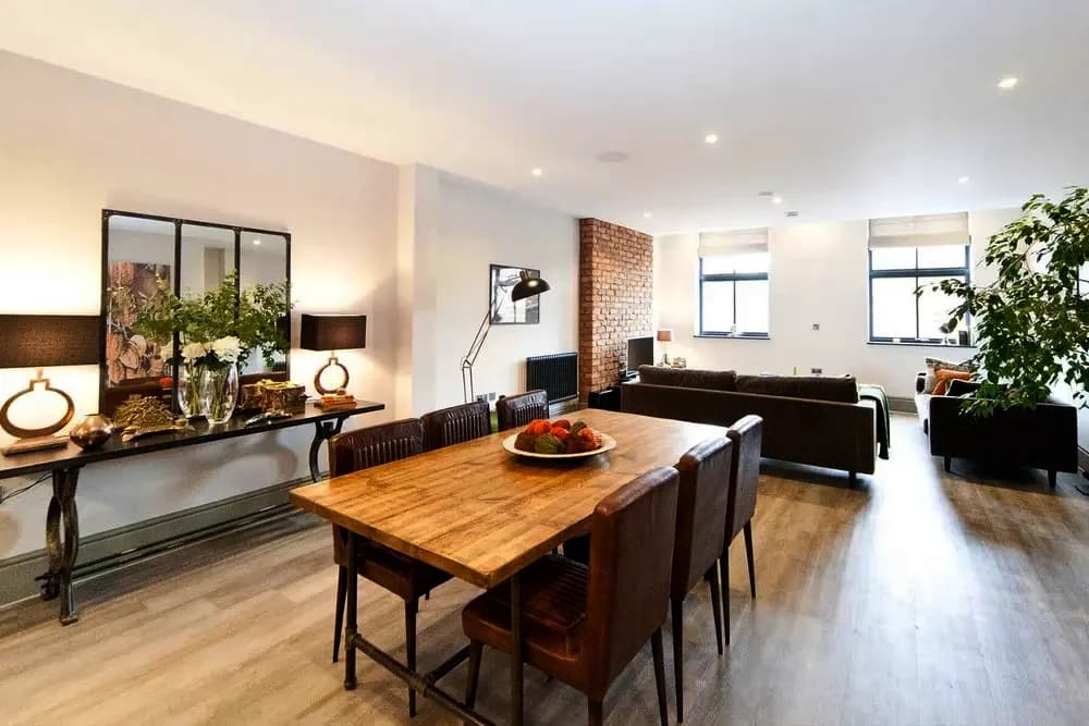 An open-plan living and dining room at Clement House, Birmingham, with an exposed brick wall